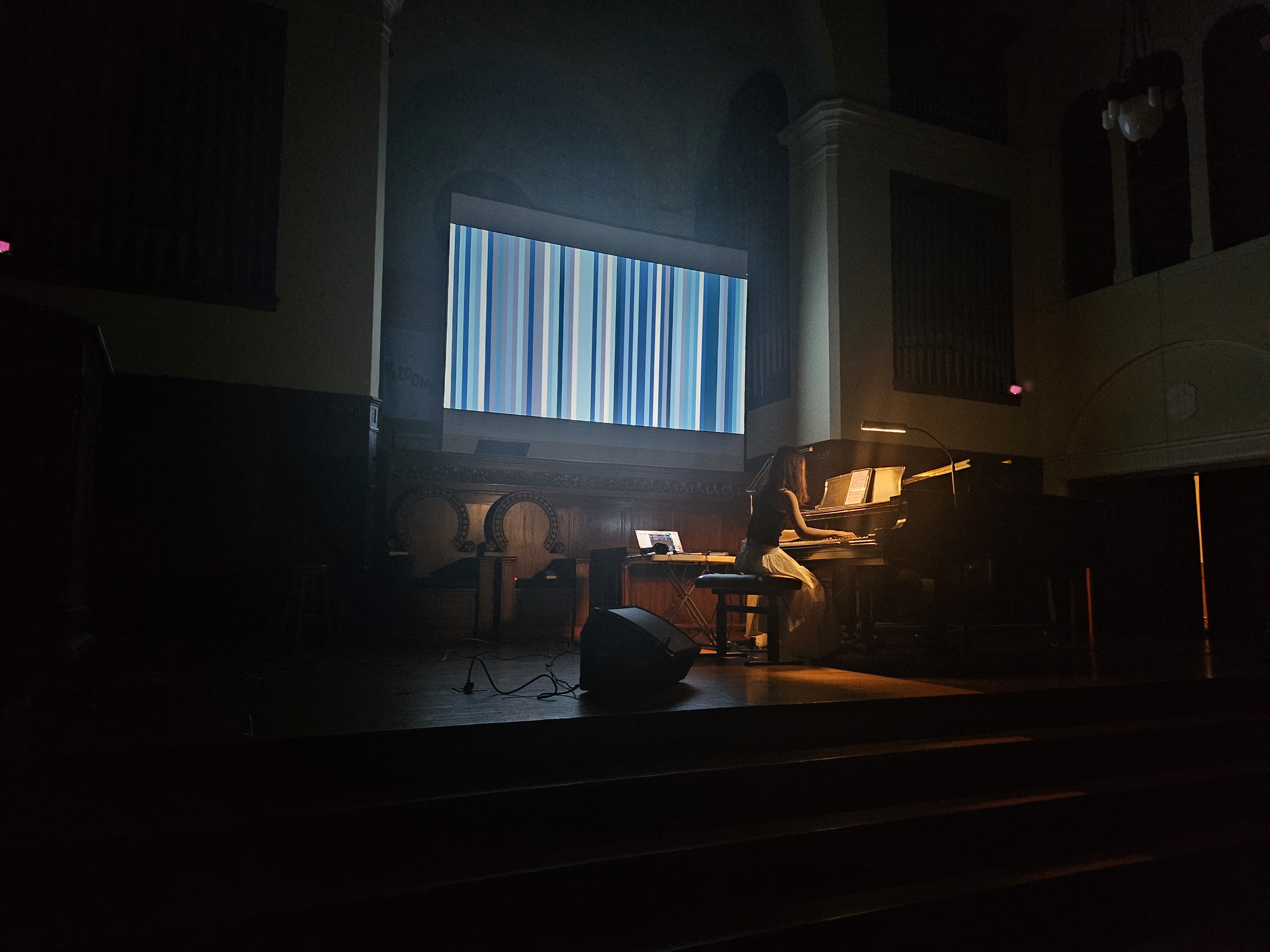 Recital in a darkened cathedral with abstract pixel projection behind the piano